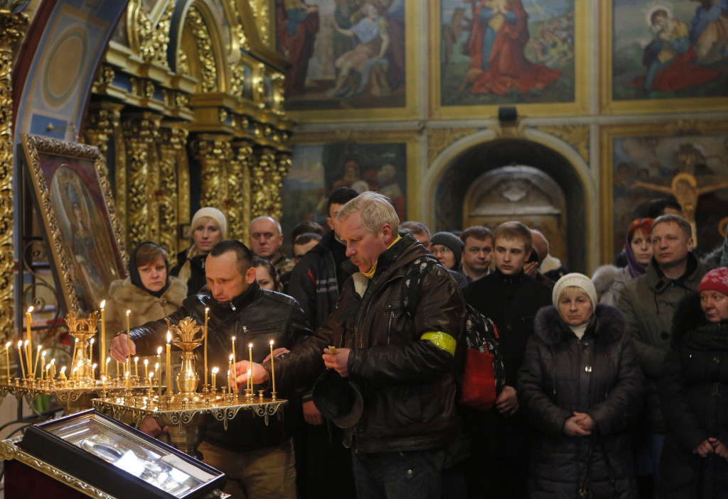 Ukrainian Orthodox believers light candles during the memorial service for the Heavenly hundreds in the Mikhaylivsky Cathedral in Kiev, Ukraine, Saturday, Feb. 20 2016. The "Heavenly Hundred" is what Ukrainians in Kiev call those who died during months of anti-government protests in 2013-14. (AP Photo/Sergei Chuzavkov)