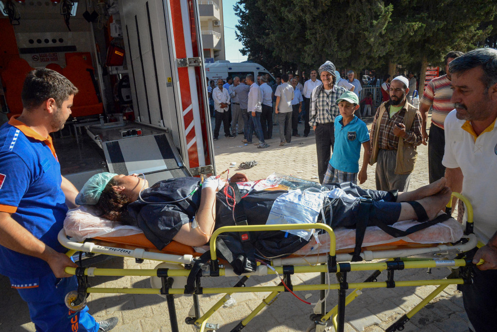 En kvinna som har blivit skadad i IS bombanfall i Kobane i Syrien får hjälp till sjukhuset. Foto: AP/TT