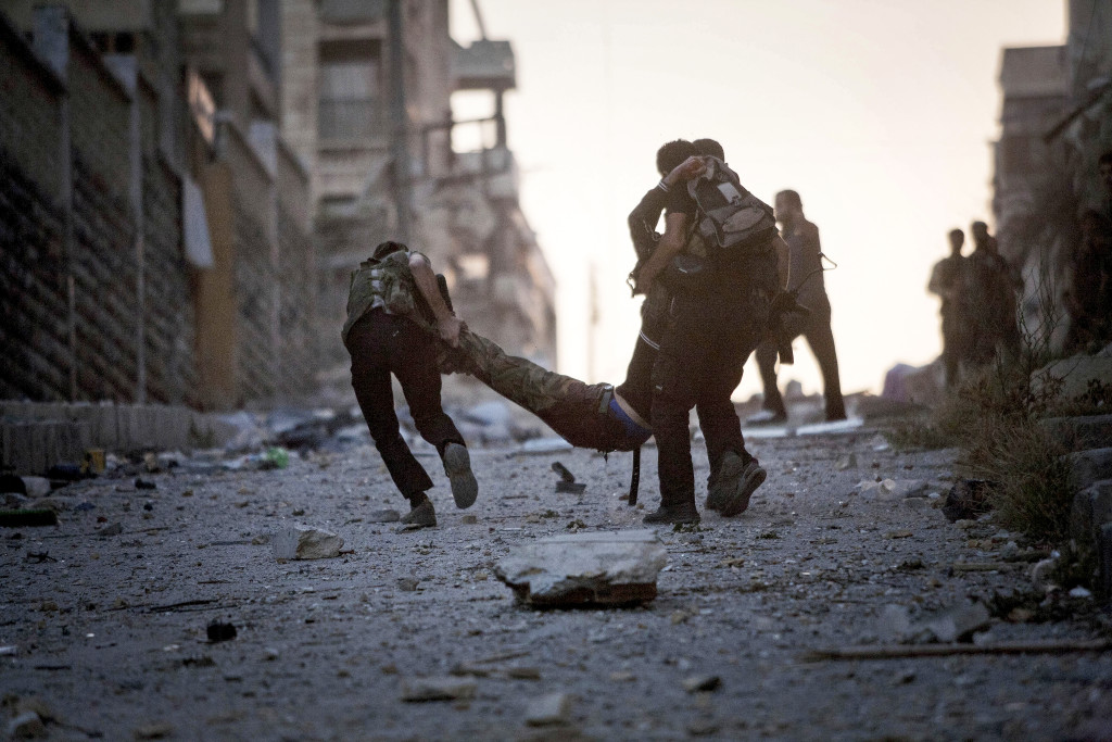 Soldater i FSA (Fria syriska armén) hjälper en allvarligt skadad kamrat, skjuten av en krypskytt från syriska armén i Aleppo. Foto: Manu Brabo/AP Photo/TT.