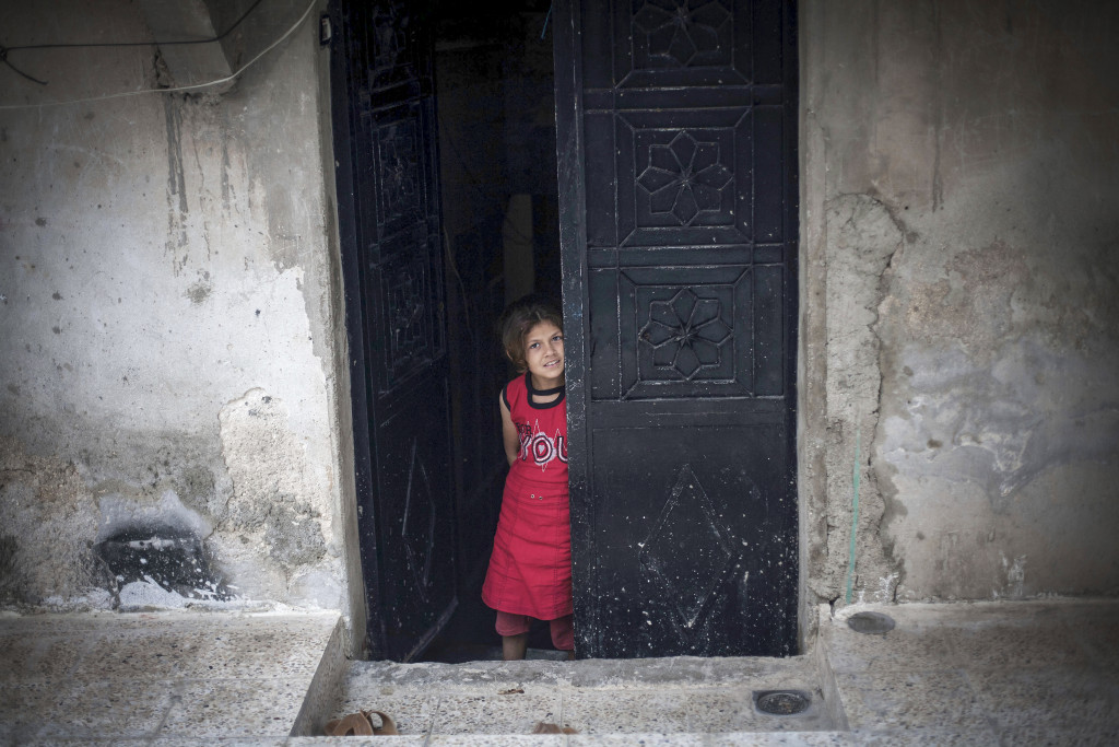 En syrisk flicka står i dörren till sitt hem där FSA och syriska armén strider i Amariyadistriktet i Aleppo, september 2012. Foto: AP Photo/ Manu Brabo/TT.