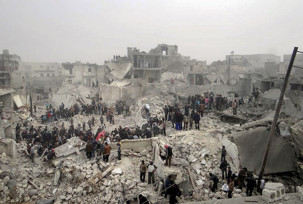 Denna bild tagen av en privatperson visar människor som söker igenom bråten från en byggnad sönderbombad av syriska statliga armén i Jabal Bedro-området i Aleppo februari 2013. Foto: Aleppo Media Center AMC/AP Photo/TT.